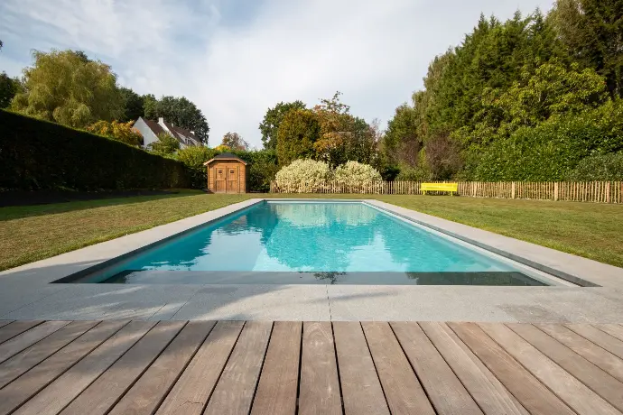 Piscine moderne avec plage en bois et margelles grises — Le Petit Baigneur