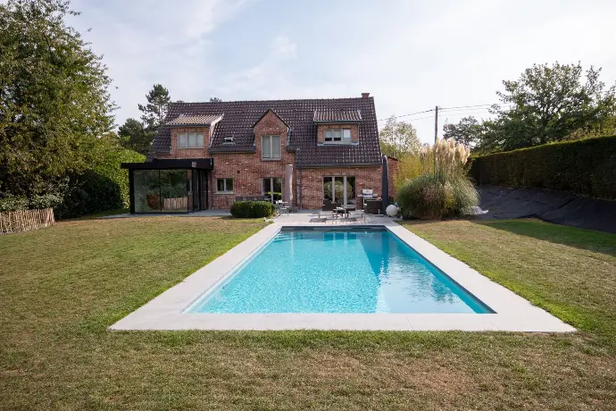 Piscine rectangulaire devant une maison en briques — Le Petit Baigneur