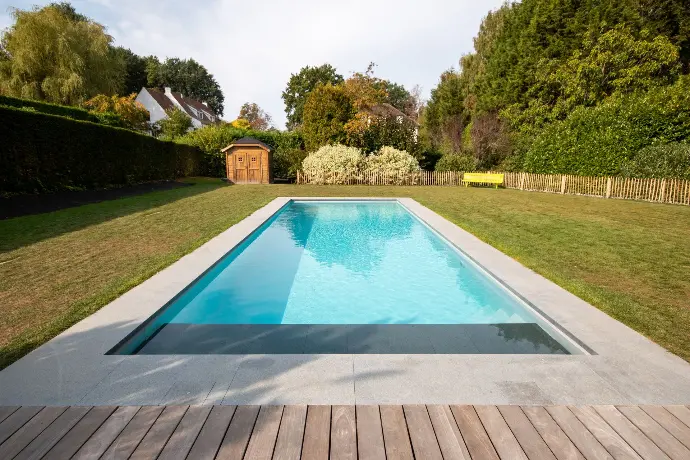 Piscine extérieure avec terrasse en bois et haies vertes — Le Petit Baigneur