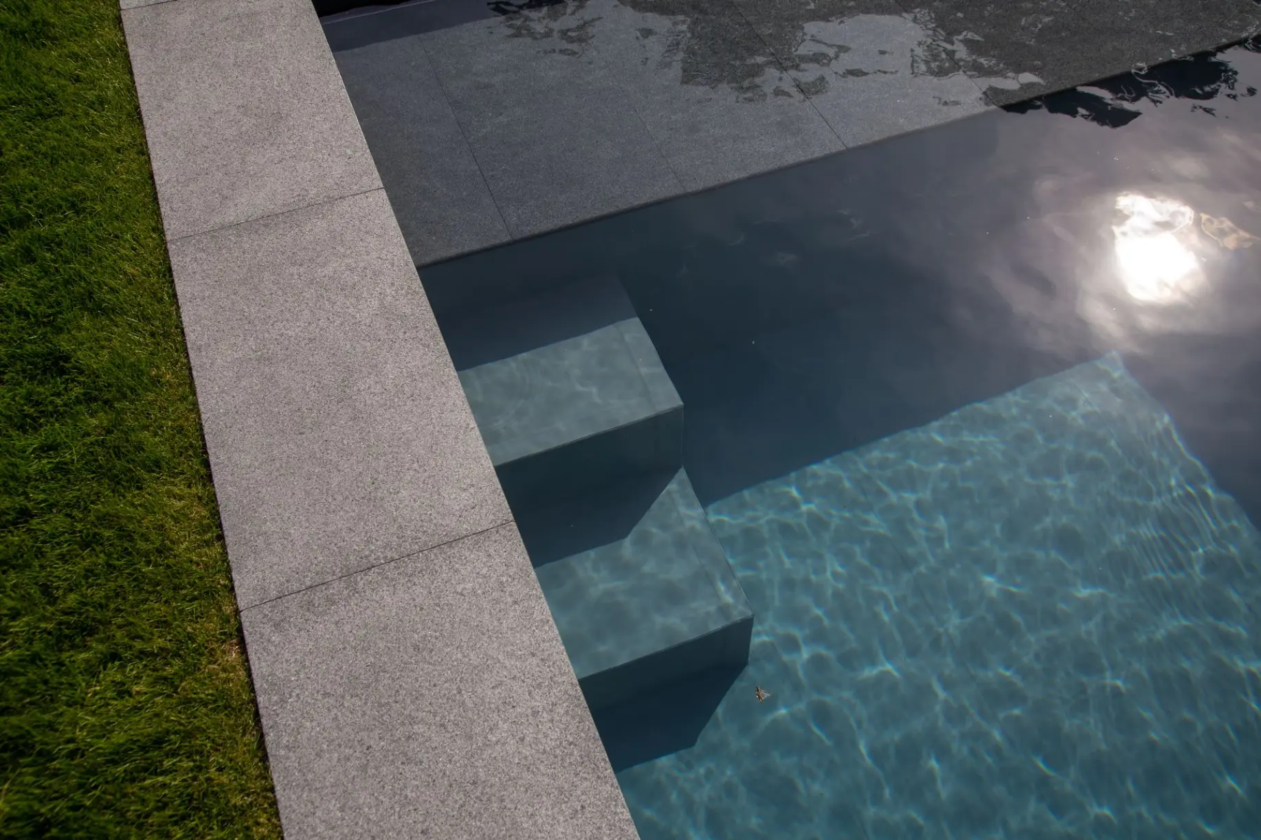 Piscine minimaliste en pierre grise avec escalier submergé — Le Petit Baigneur