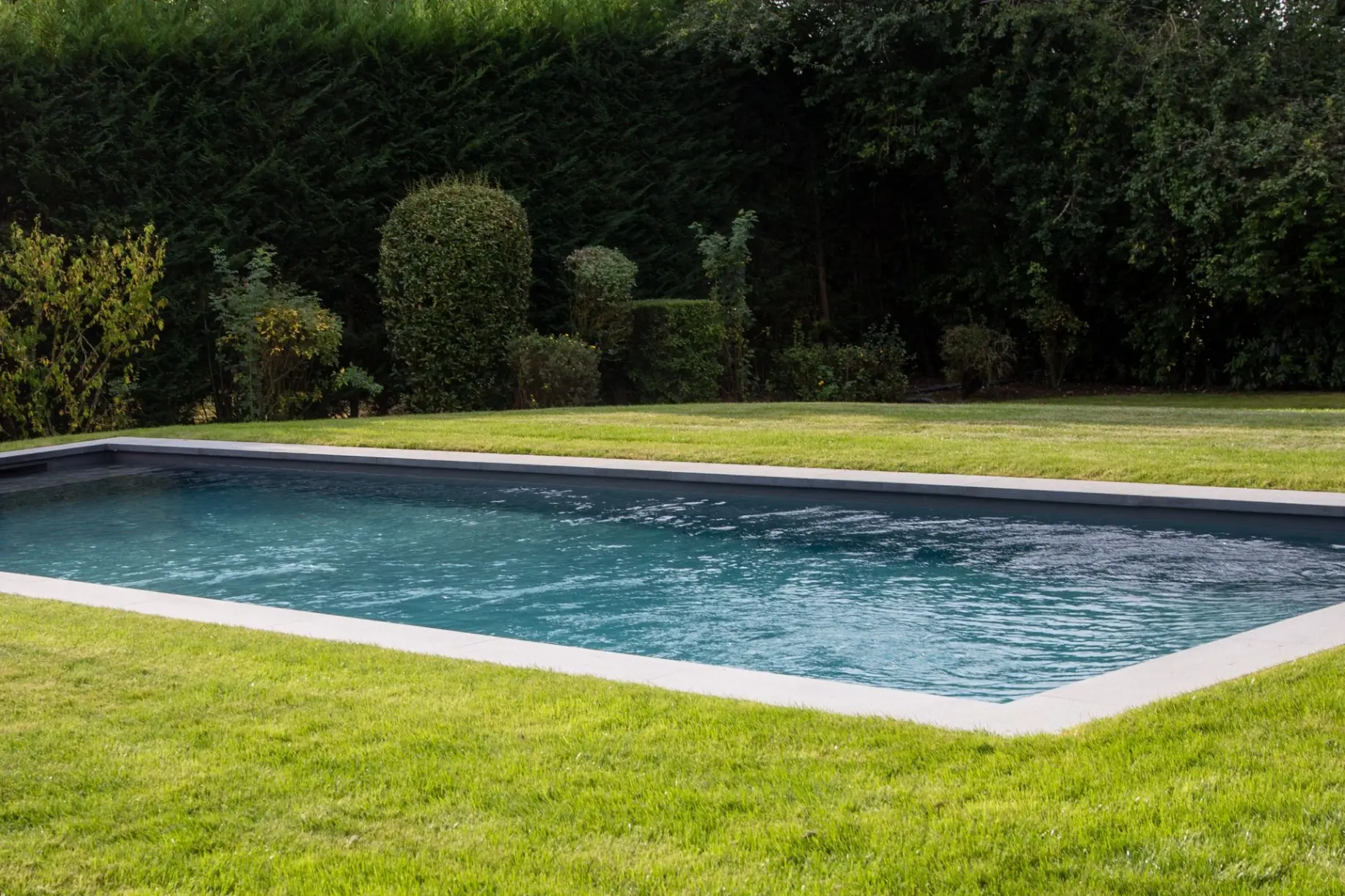Piscine avec reflets bleus et plage immergée — Le Petit Baigneur