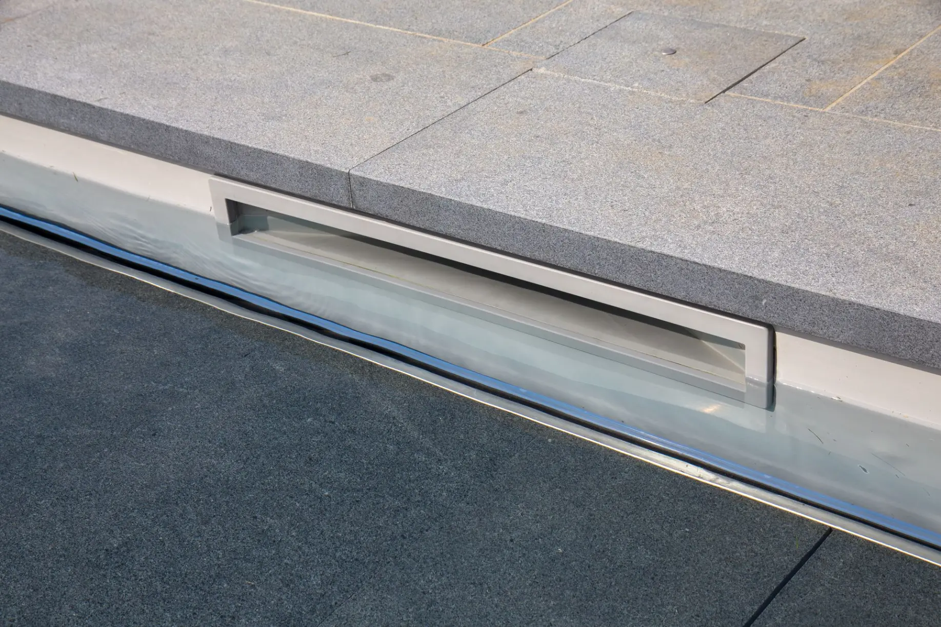 Détail de margelle grise au bord d’une piscine — Le Petit Baigneur