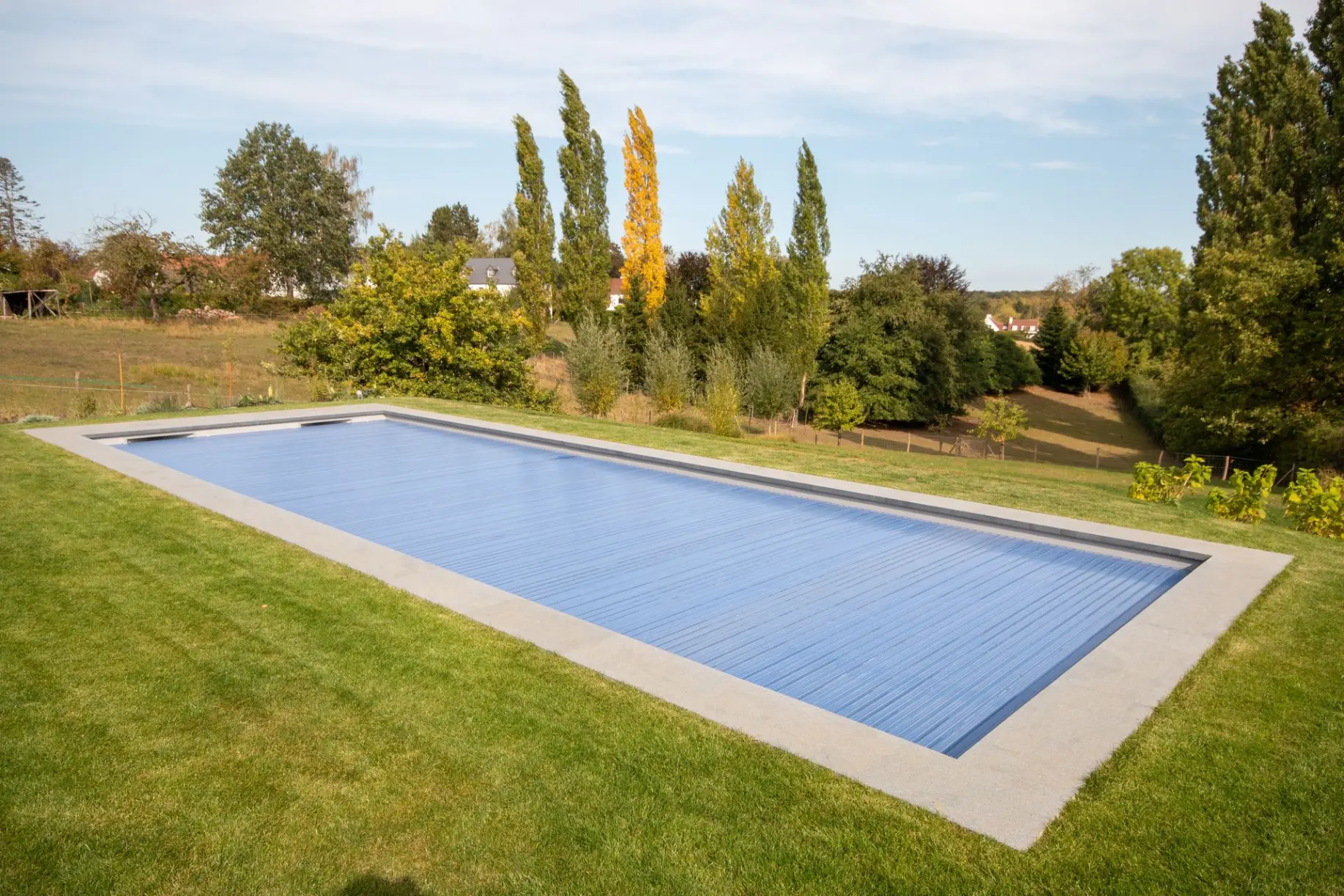 Piscine paysagère avec margelles en pierre et verdure — Le Petit Baigneur