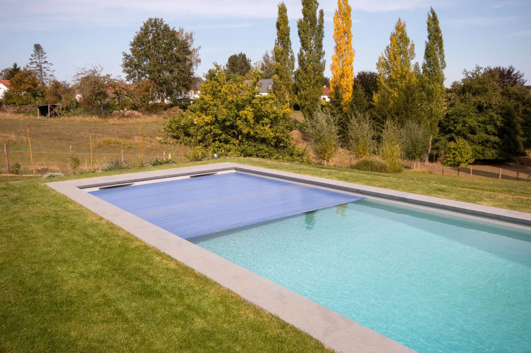 Piscine familiale entourée d’arbres et pelouse — Le Petit Baigneur