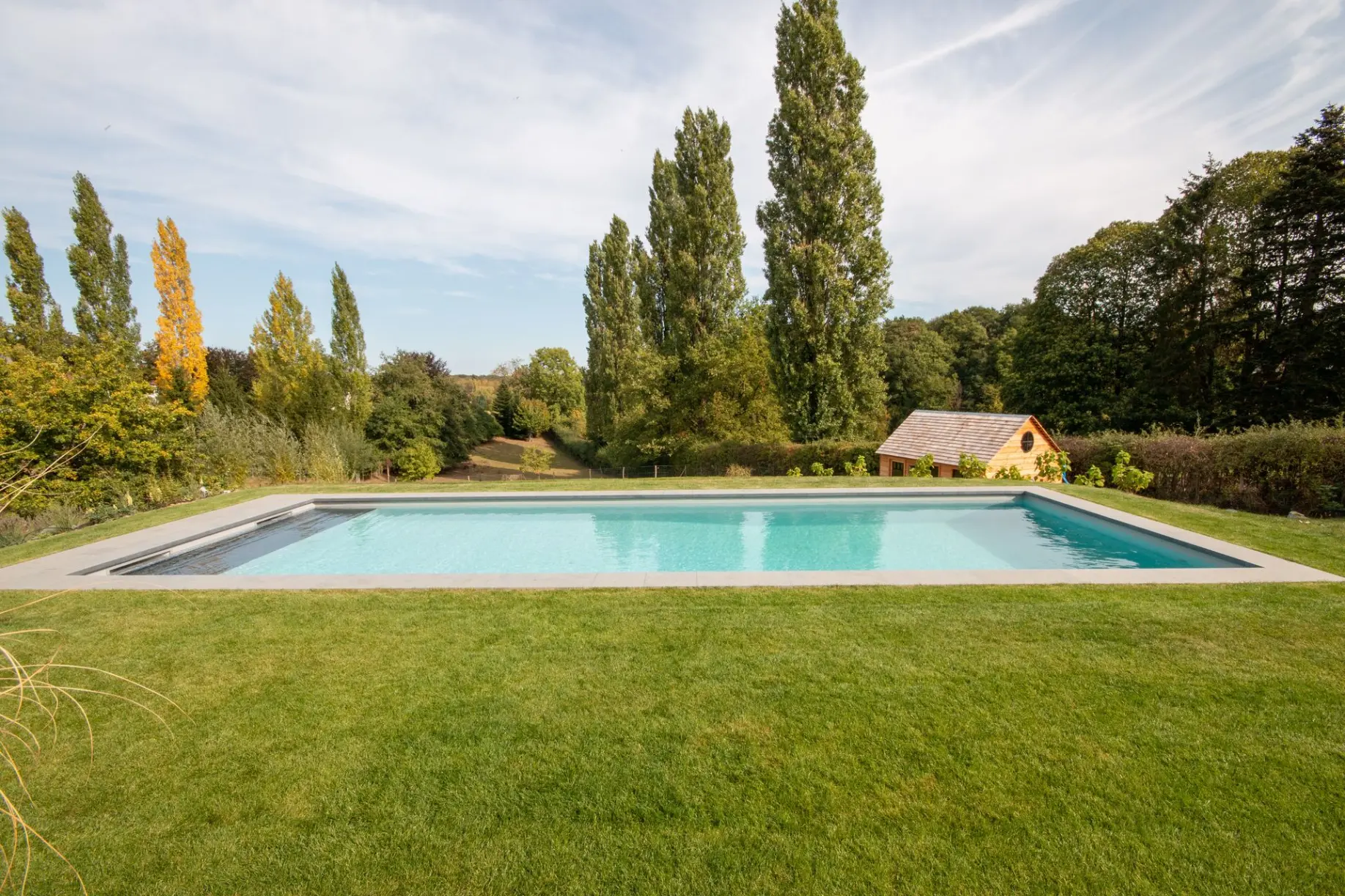 Piscine de détente entourée d’arbres et de gazon — Le Petit Baigneur