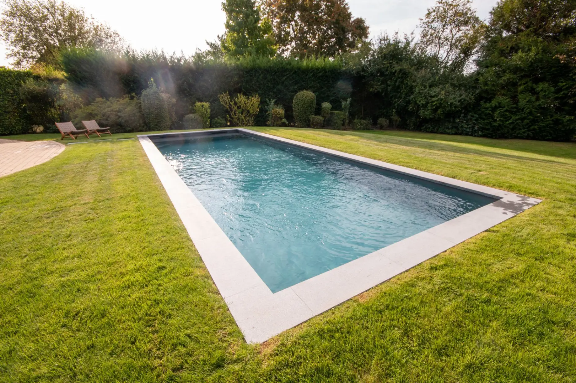 Piscine de jardin avec pelouse et bordure en pierre claire — Le Petit Baigneur