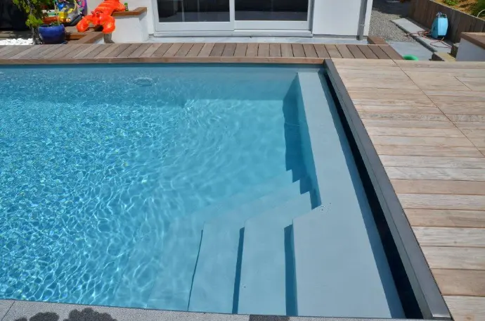 Piscine contemporaine avec margelles claires et eau bleue — Le Petit Baigneur