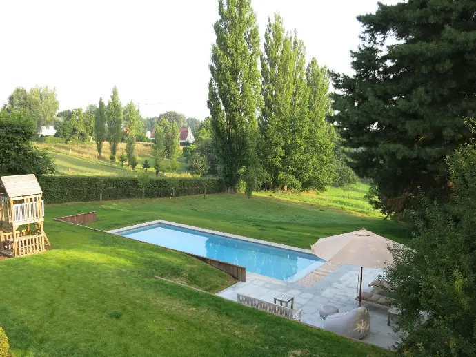 Piscine entourée de pelouse et d’arbres — Le Petit Baigneur
