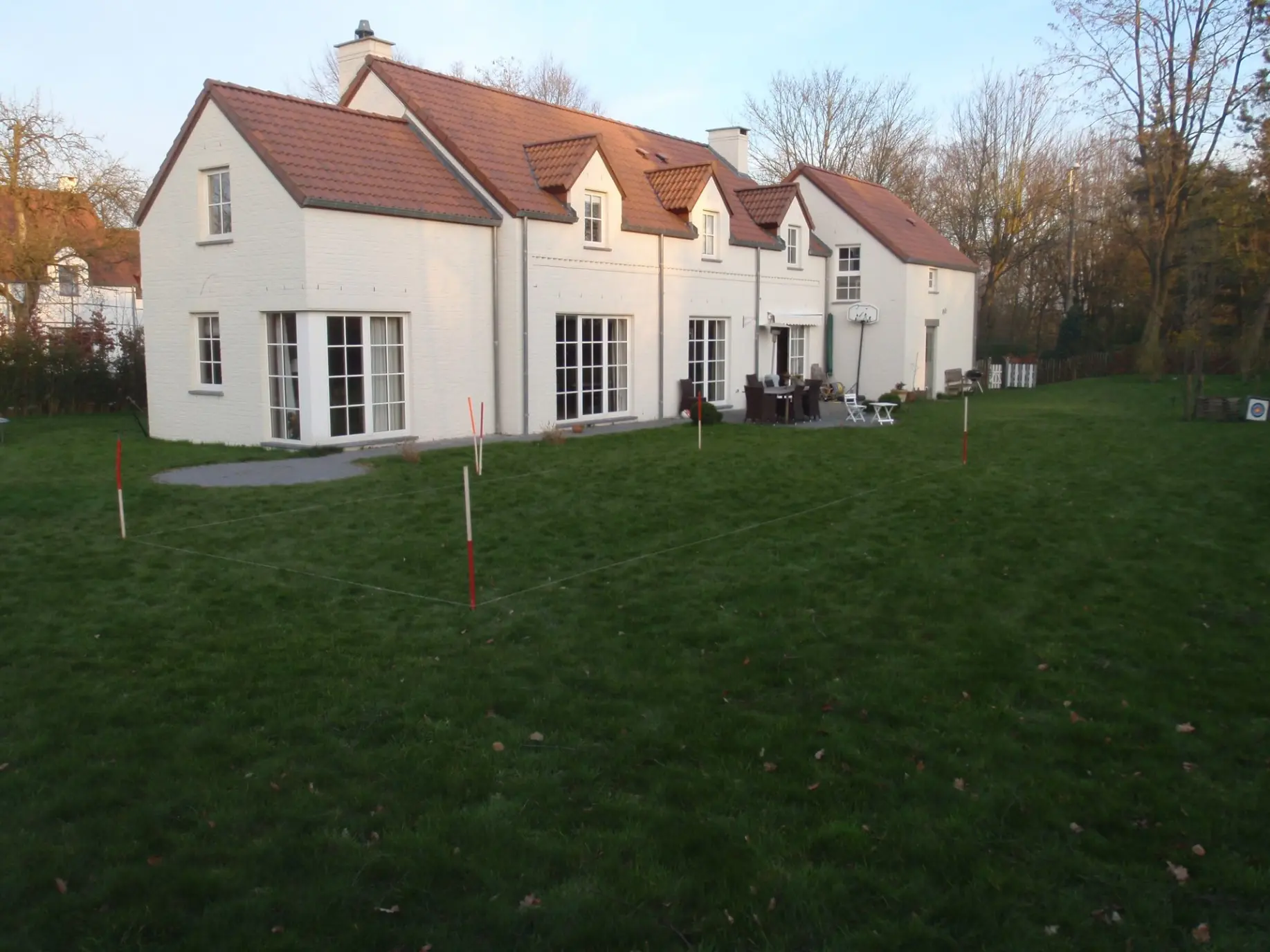 Implantation piscine devant maison blanche à toiture rouge – Orientation ensoleillée