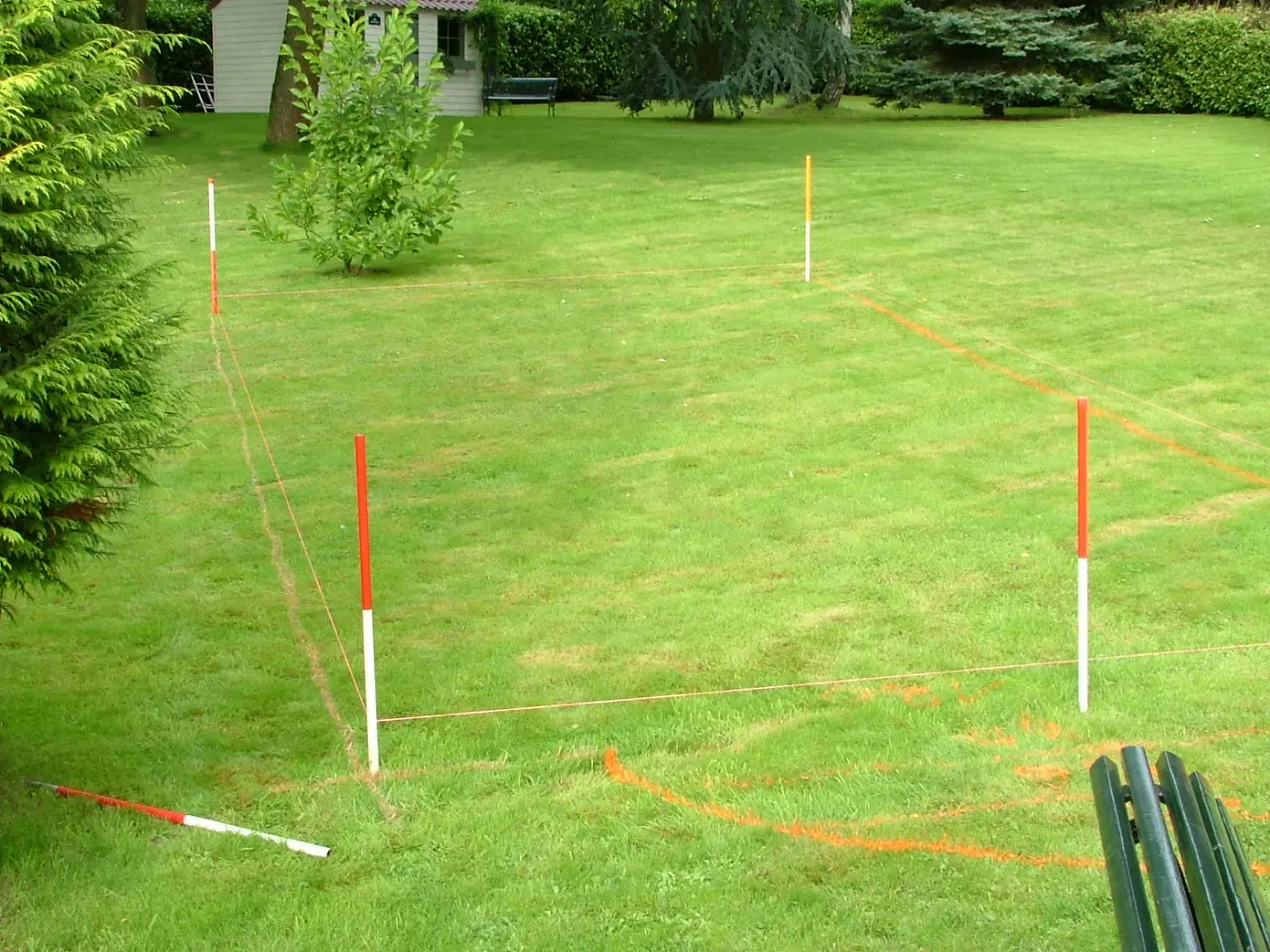 Implantation de piscine sur pelouse verte avec piquets rouges et cordeau